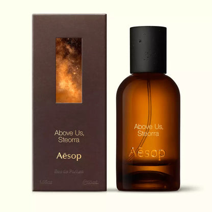 Amber glass Aesop Above Us, Steorra Eau de Parfum bottle beside its brown outer box on a white background.