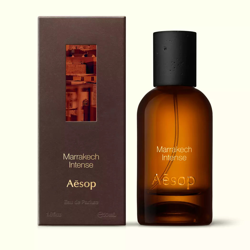 Amber glass Aesop Marrakech Intense Eau de Parfum bottle beside its brown outer box on a white background.