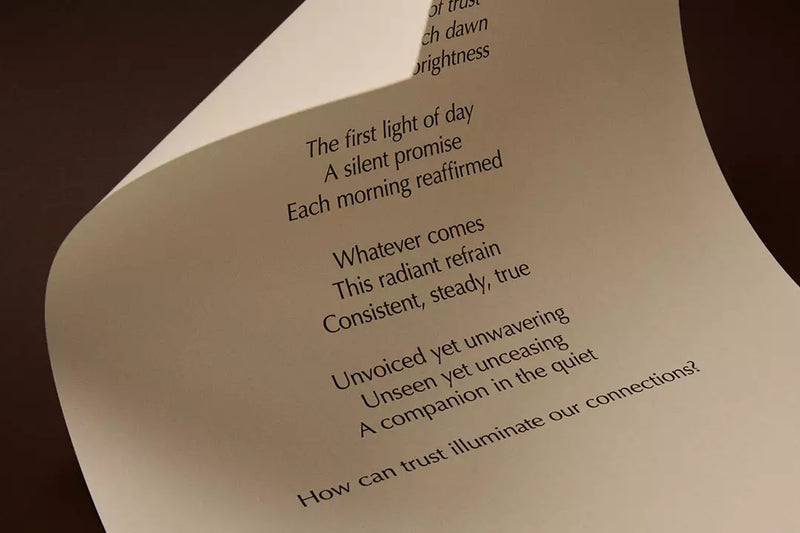 Curved cream page with printed verse against a dark brown background.