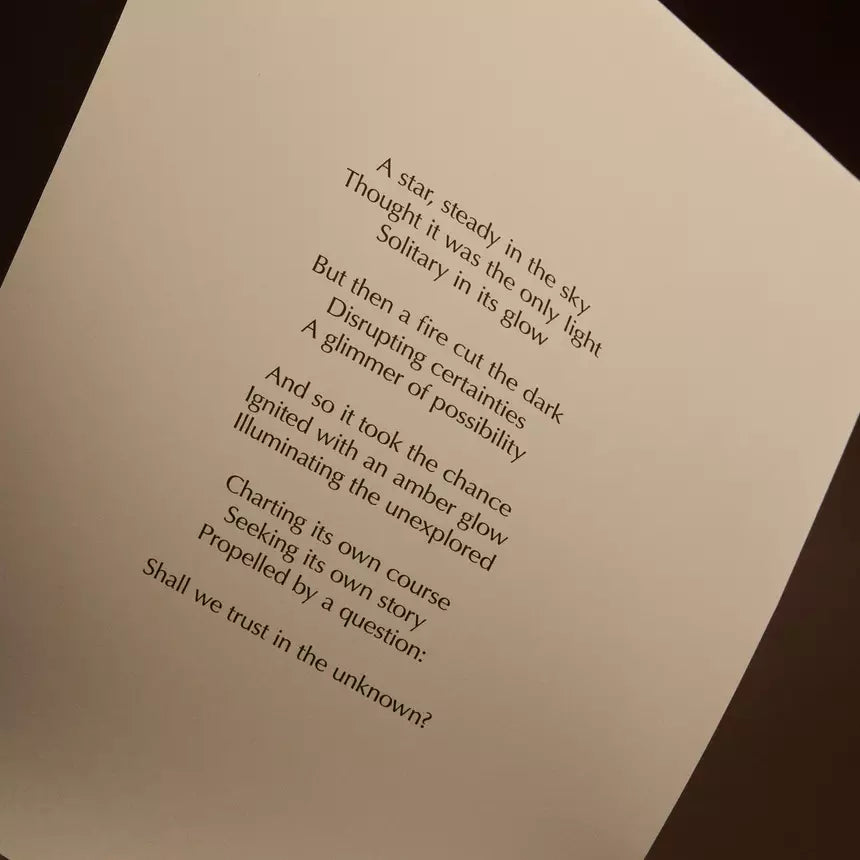 Curved cream page with printed verse against a dark brown background.