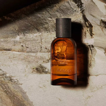 Aesop Boundless Eremia bottle on a pale veined stone surface.
