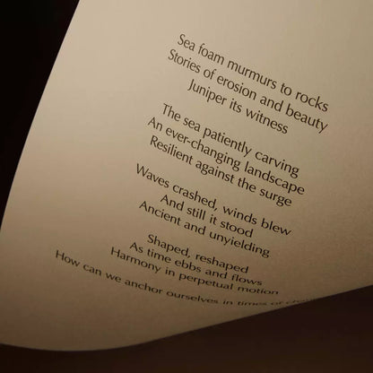 Curved cream page with printed verse against a dark brown background.