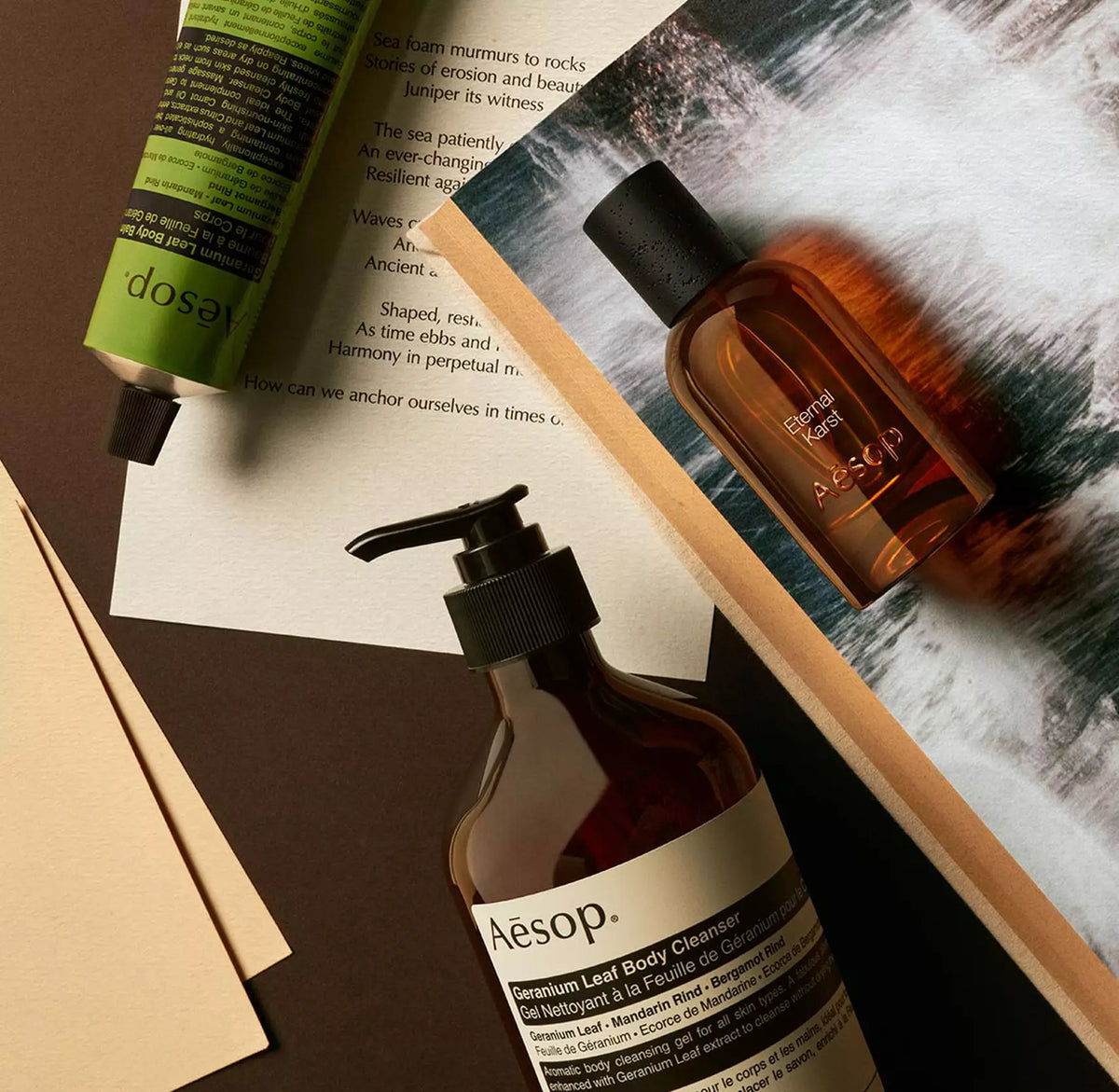 Aesop Eternal Karst bottle with pump bottle and green tube arranged on papers with foaming water imagery.