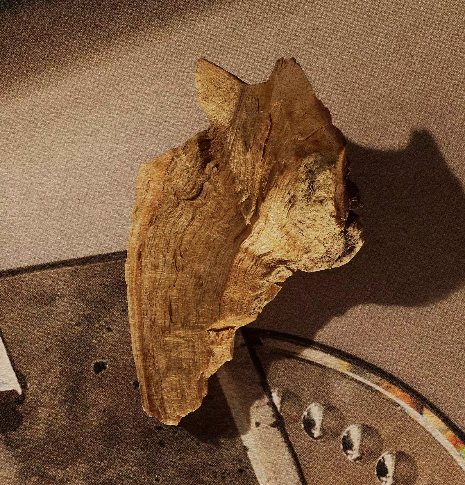 Piece of wood resting on stacked mirrored trays.