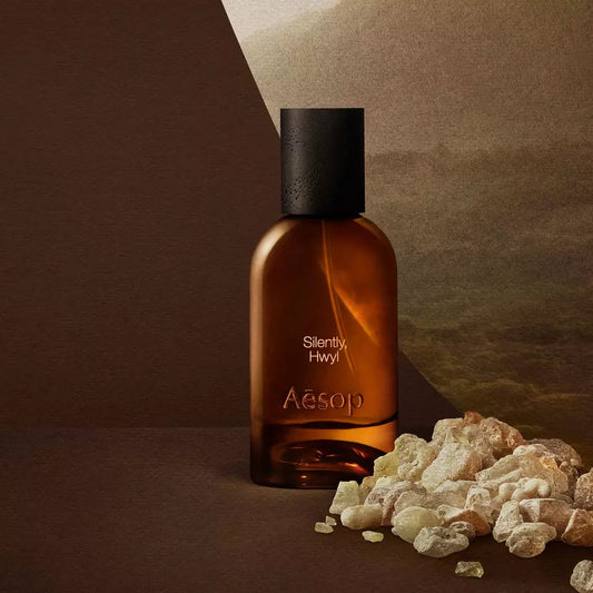 Aesop Silently Hwyl bottle beside resin stones on a dark surface.