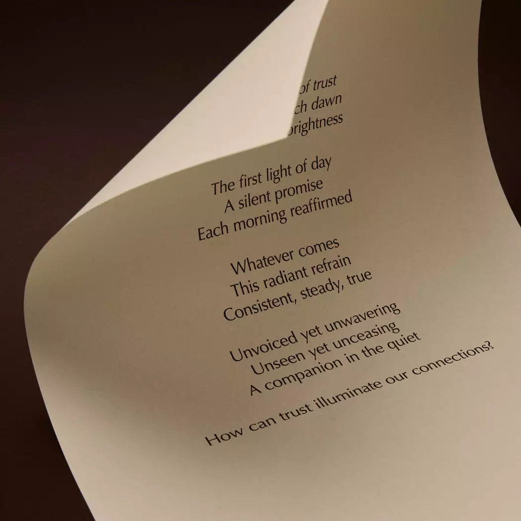 Curved cream page with printed verse against a dark brown background.