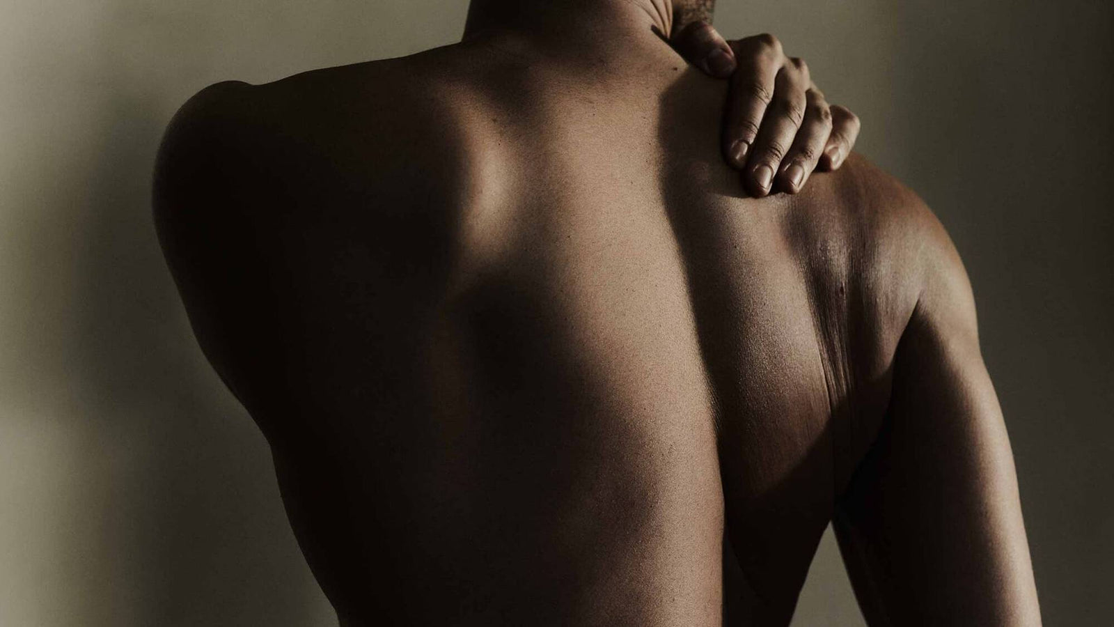 Person's bare back with one hand resting on their shoulder.